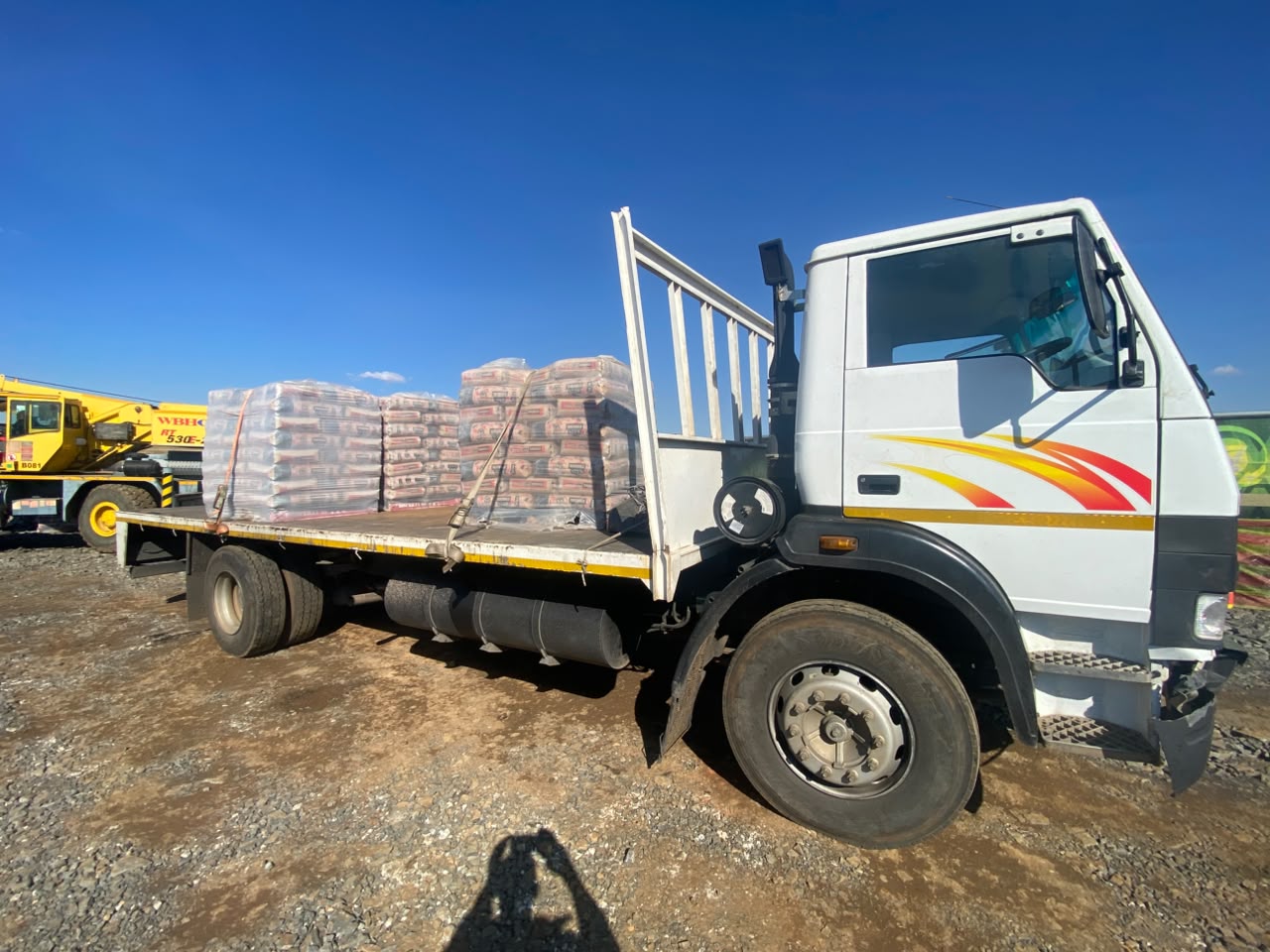 Flat-deck truck carrying a strapped load of cement bags